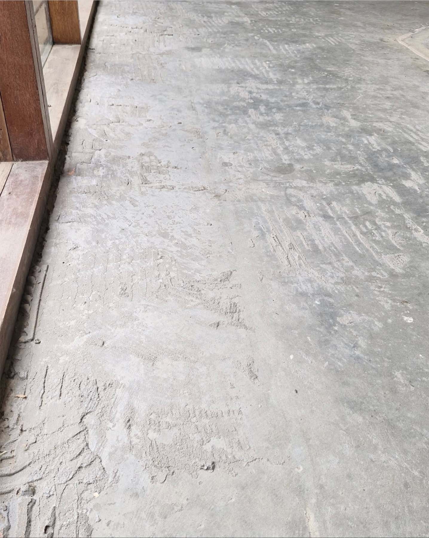 Close-up of a textured grey concrete floor and wooden frame.