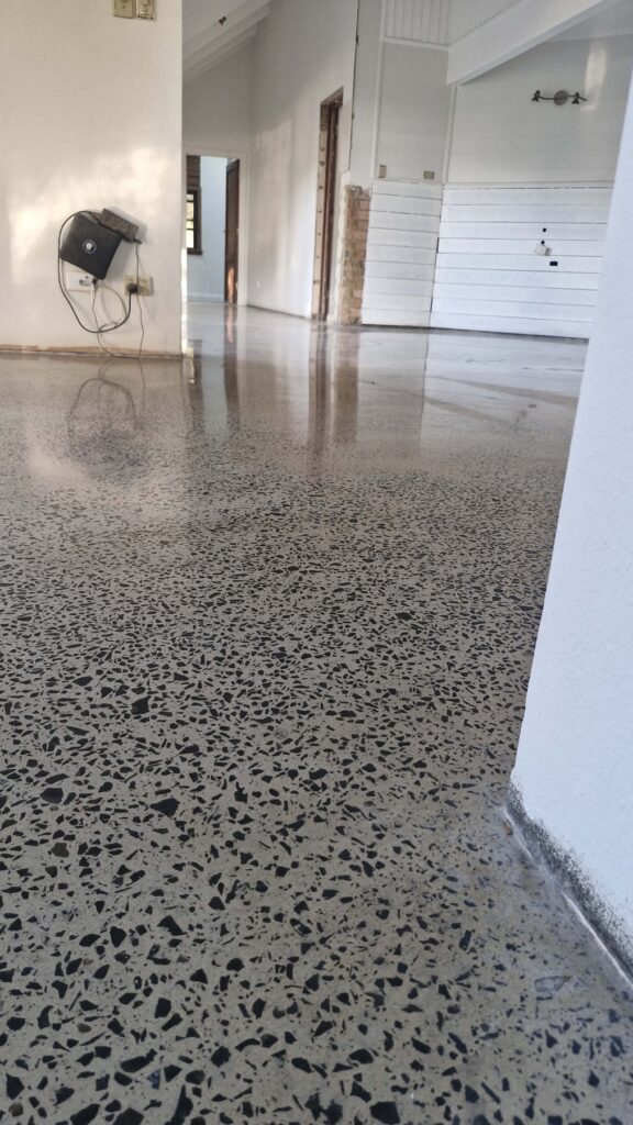 High-gloss polished concrete floor with black aggregate finish.