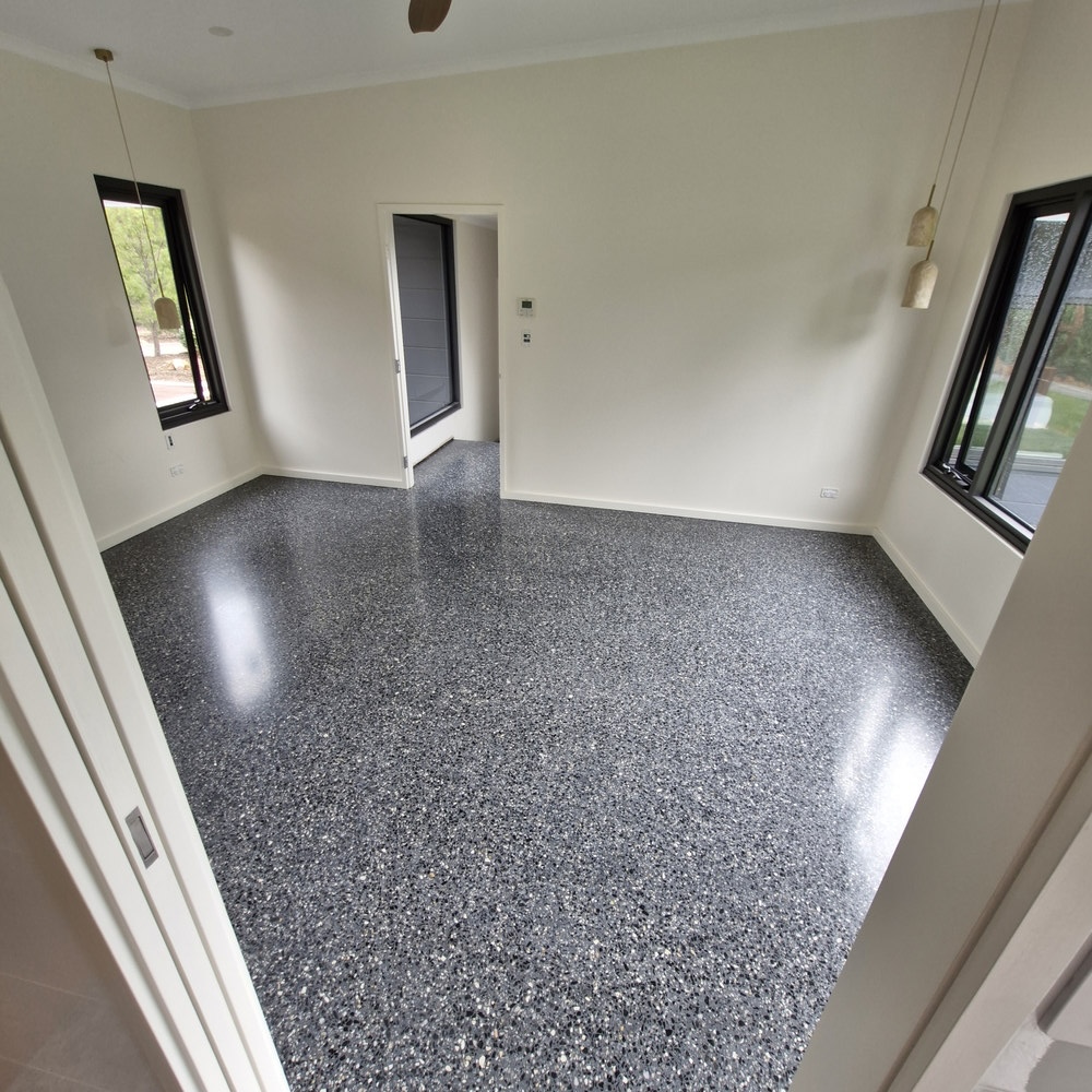 Polished dark grey speckled concrete floor in a modern room.