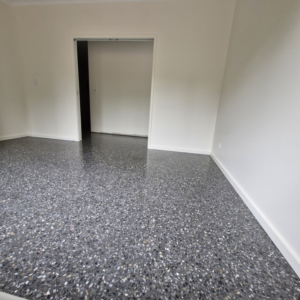 Polished grey aggregate concrete floor in an empty modern room.