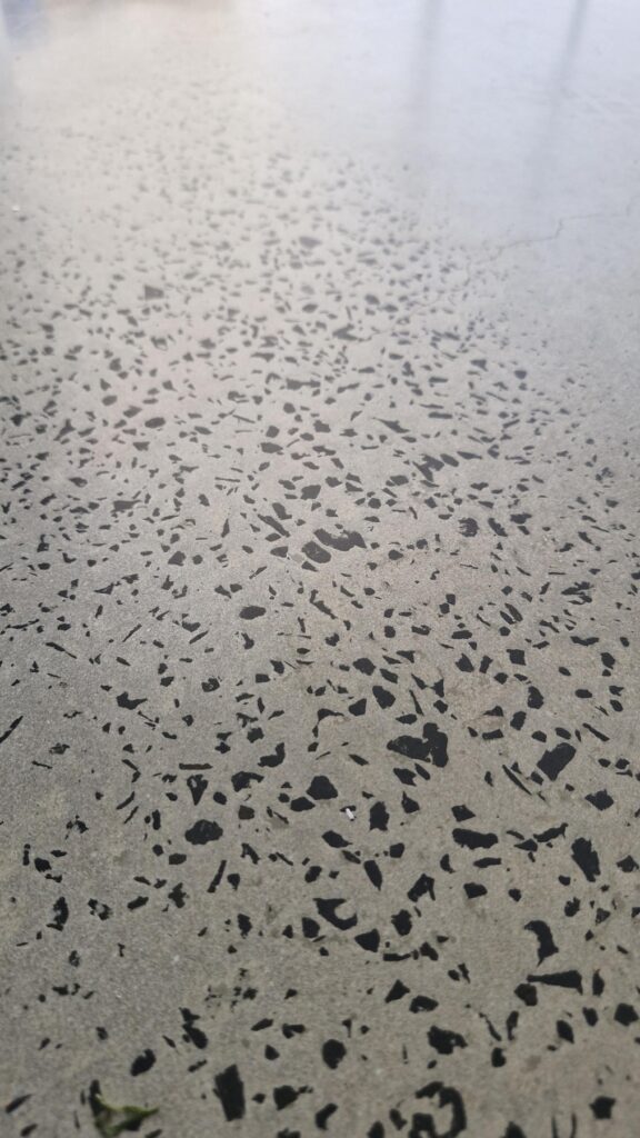 Polished concrete floor with exposed dark stone aggregate finish.