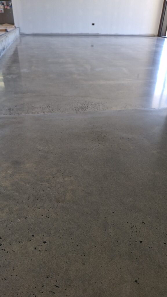 Highly polished grey concrete floor reflecting light in a room.