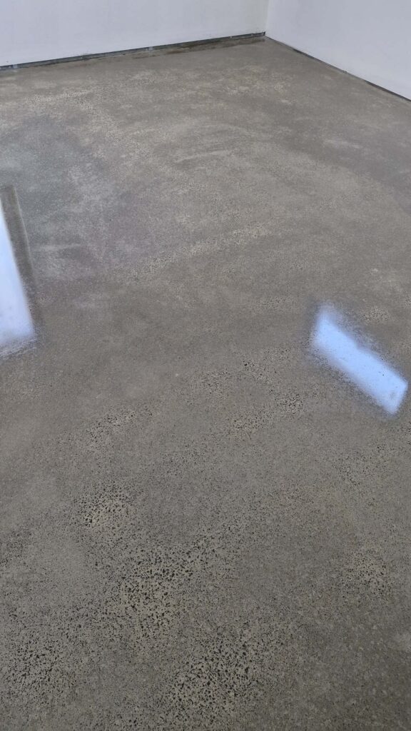 Polished concrete floor with light reflections and white walls.
