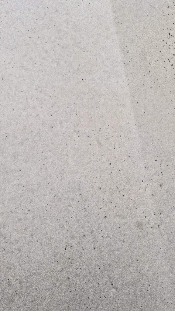 Close-up of a textured grey concrete surface with dark speckles.